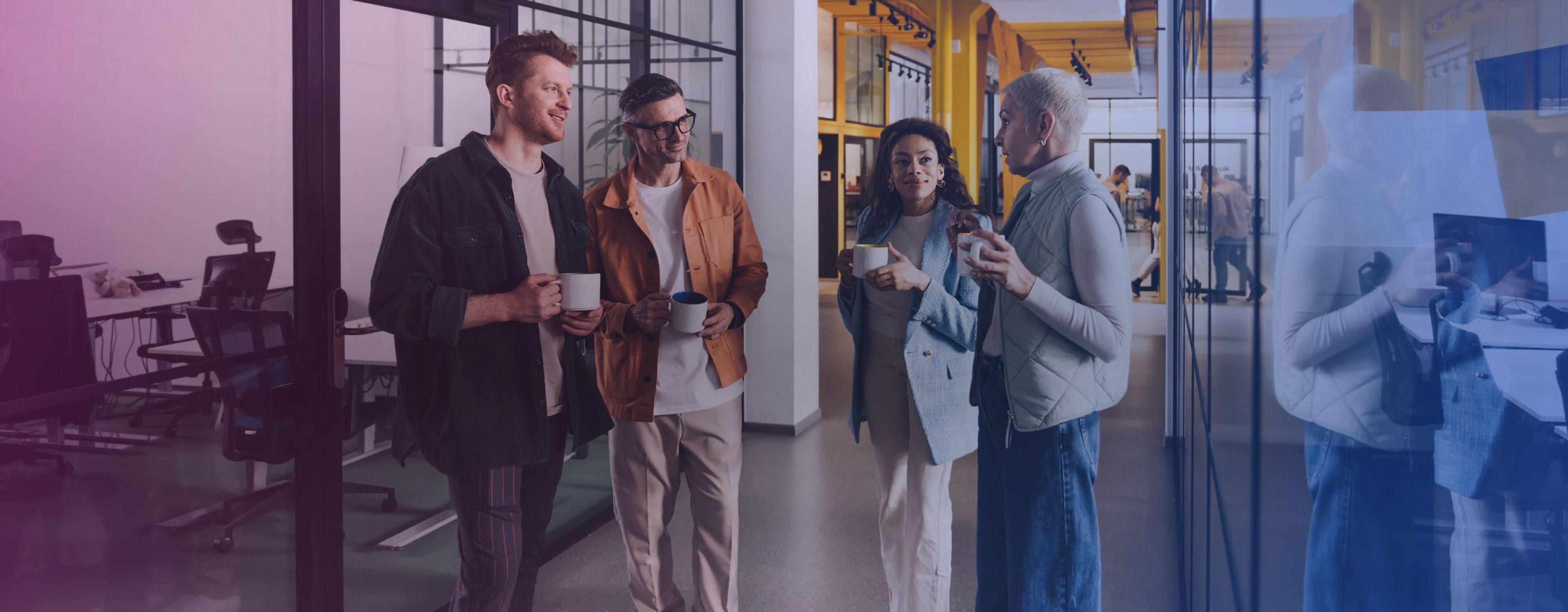 A group of people in the office drinking tea and coffee whilst in conversation
